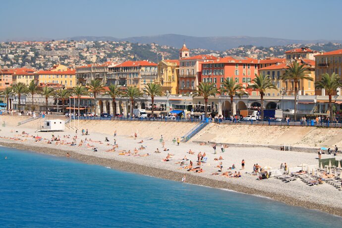 A sunny view of Nice’s famous Promenade des Anglais lined with palm trees and colorful historic buildings