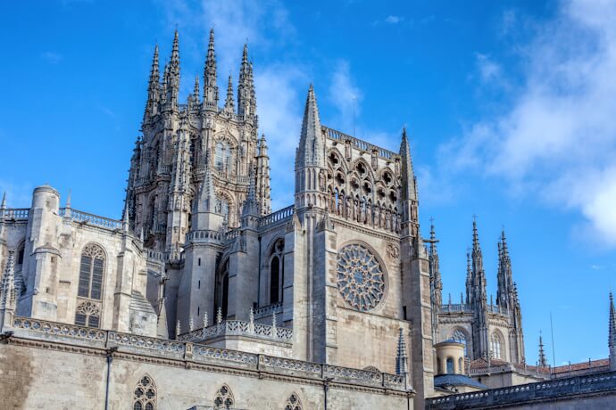 Majestic Gothic spires and ornate stonework of Burgos Cathedral rising against a bright blue sky in northern Spain.