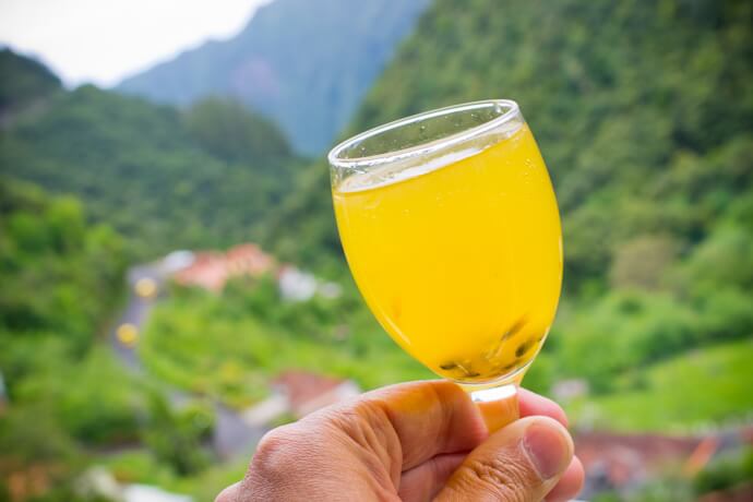 Glass of Madeira poncha with mountain views.