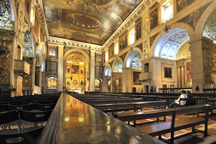 Interior of the Church of São Roque, featuring richly decorated chapels and a painted ceiling, in Lisbon, Portugal.