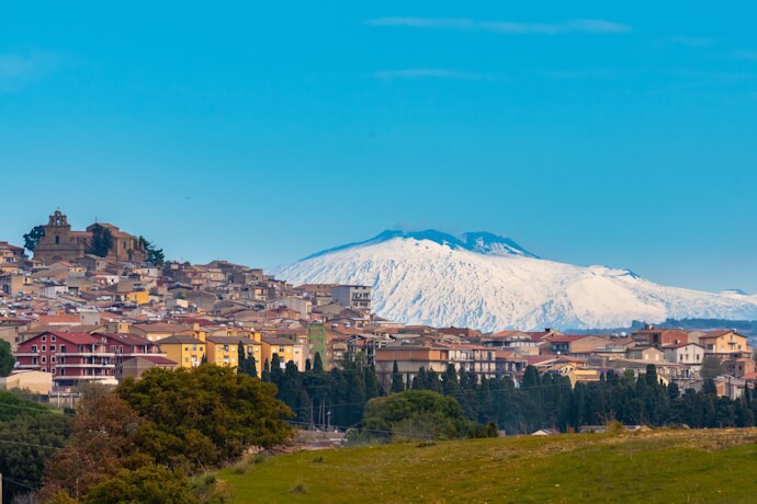 A charming Sicilian town sits under the watchful, snow-capped gaze of Mount Etna