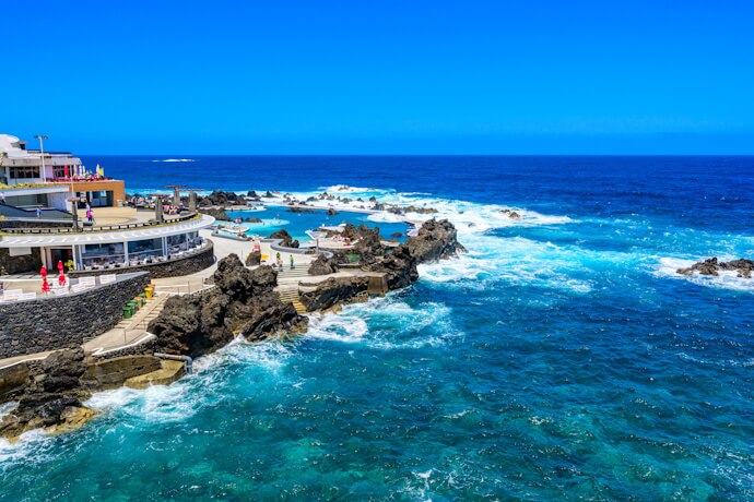 Rocky volcanic pools filled with clear blue water in Porto Moniz, Madeira