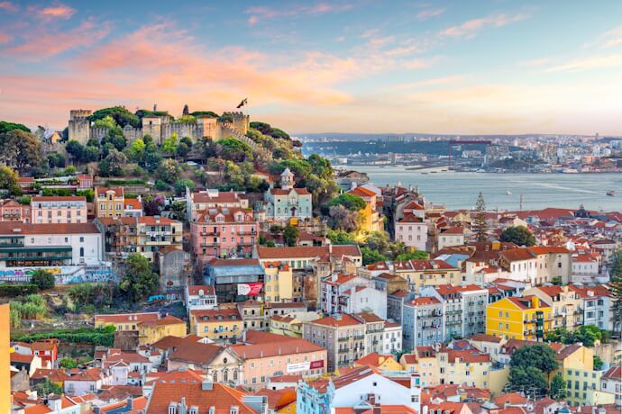 Panoramic view of Alfama, São Jorge Castle, and the Tagus River in Lisbon at sunset