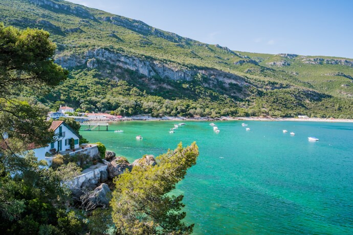 Turquoise waters and limestone cliffs at Portinho da Arrábida in Arrábida Natural Park, Portugal