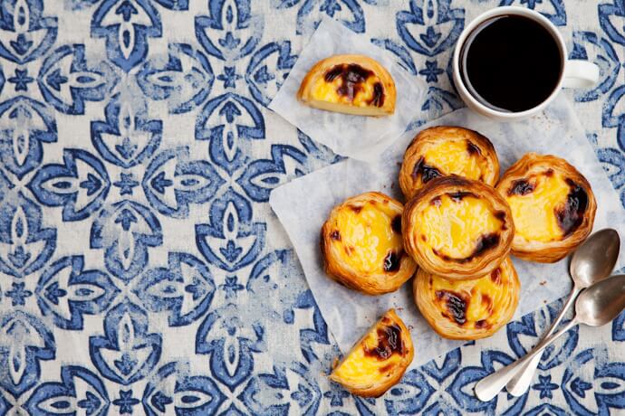 Pastéis de nata served with coffee on traditional Portuguese azulejo tiles in Lisbon