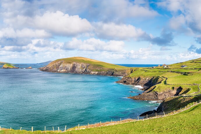Ireland’s coastline with green cliffs and turquoise Atlantic waters along the Dingle Peninsula.