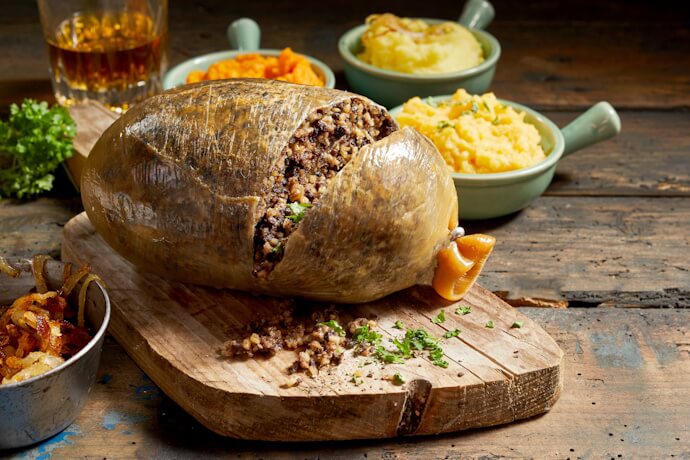 A freshly served haggis with traditional Scottish side dishes.
