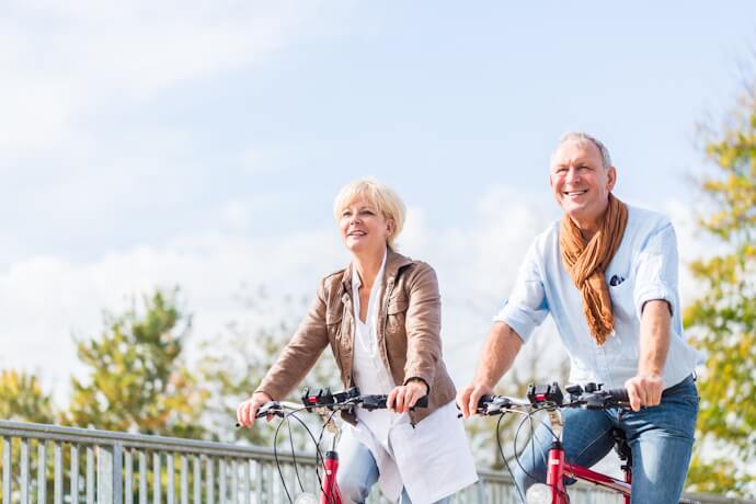 A happy senior couple riding bicycles outdoors on a sunny day, enjoying a relaxed and joyful moment together.