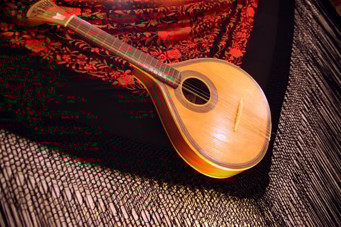 Portuguese guitar resting on a red and black embroidered shawl, symbolizing a traditional Fado music performance.