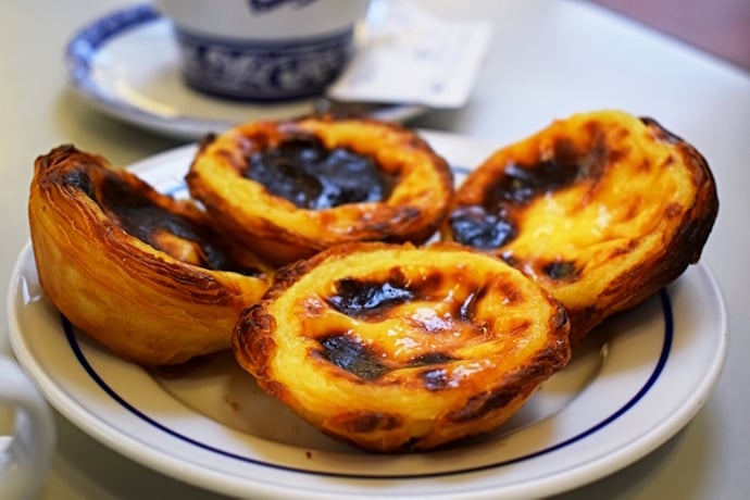 Close-up of freshly baked pastéis de nata with caramelized tops served on a white plate.