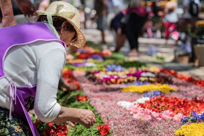 Woman arranging flowers on a street during the Madeira Flower Festival in Funchal, Portugal