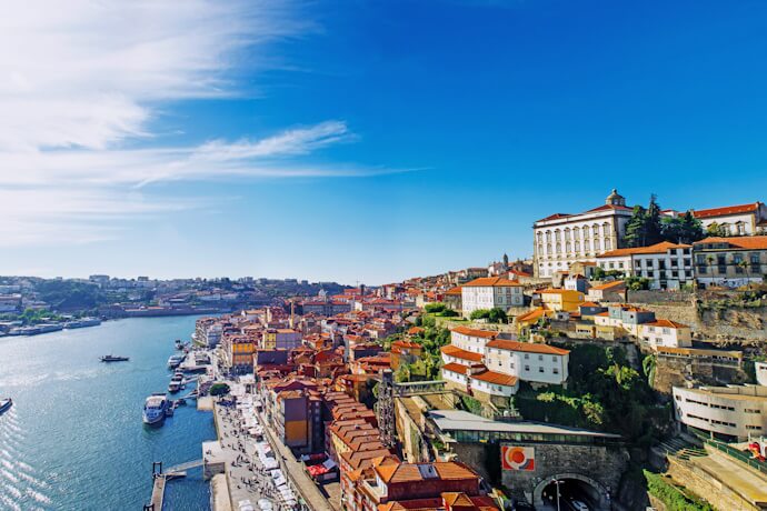 Panoramic view of Porto’s historic riverside with colorful houses, the Douro River, and traditional boats along the waterfront.