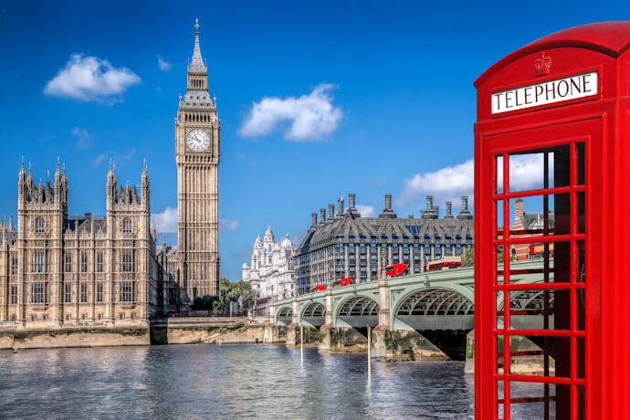 View of Big Ben and the Houses of Parliament in London, with a classic red telephone booth and Westminster Bridge.