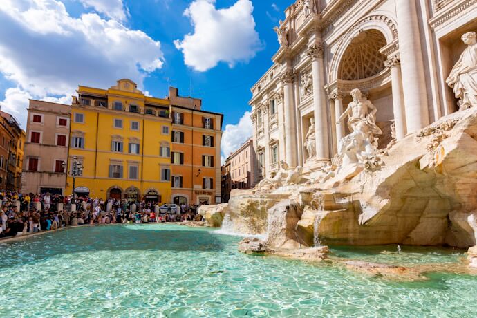 The Trevi Fountain in Rome with crystal-clear water and visitors admiring its stunning Baroque sculptures.
