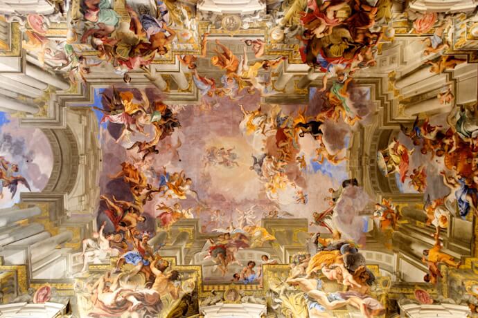 A magnificent frescoed ceiling inside a Vatican museum, showcasing vivid Renaissance artwork and ornate detail.
