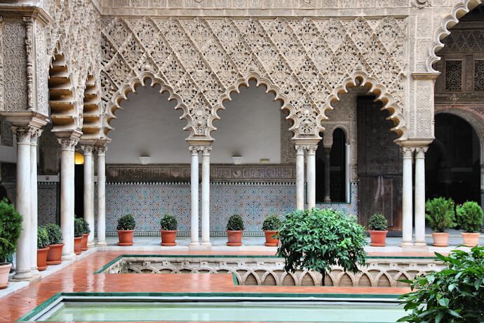 Intricate Moorish arches and a peaceful courtyard with a central fountain inside the Alcázar of Seville.