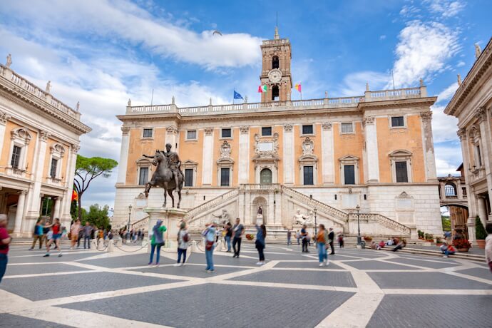 Piazza del Campidoglio on Capitoline Hill in Rome, with its grand staircase and statue of Marcus Aurelius surrounded by visitors.
