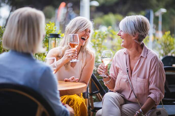 Older women chatting and drinking wine in a terrace in France.
