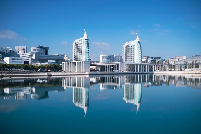 Contemporary skyline of Parque das Nações in Lisbon, with the São Gabriel and São Rafael towers reflected in the Tagus River on a clear day.