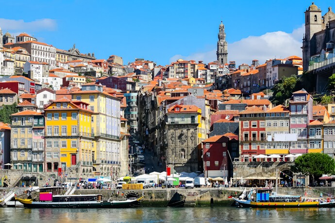 View of the Ribeira district in Porto with the Clérigos tower in the background, in front of the Douro River.