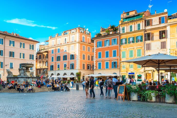 People dining outdoors in the vibrant Trastevere neighborhood, surrounded by colorful historic buildings.
