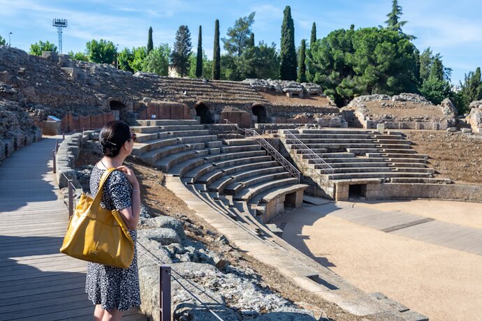 Visitor admiring the preserved stone seating and stage area of the ancient Roman Theatre in Mérida, Spain.