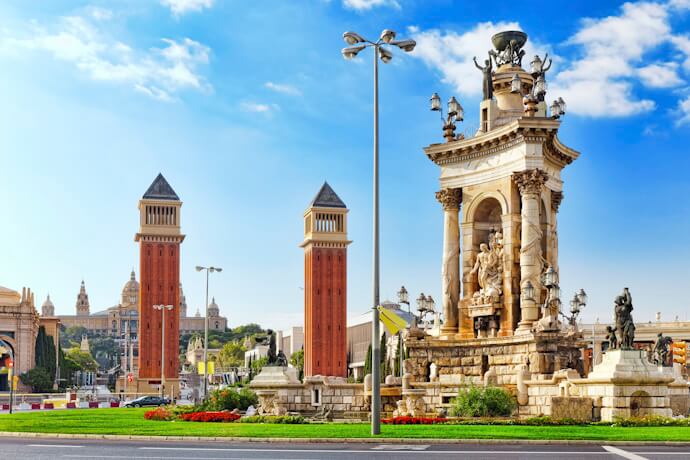 Monumental fountain at Plaça d’Espanya in Barcelona with the Venetian Towers and the National Palace in the background under a bright blue sky.
