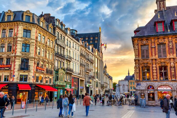 Pedestrians walking through Lille historic center at sunset
