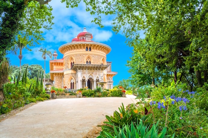 Romantic Monserrate Palace in Sintra surrounded by lush gardens under a bright blue sky.