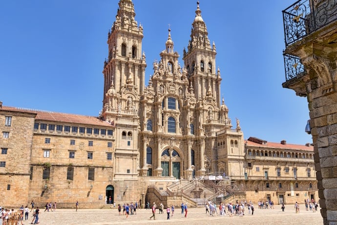 Expansive and historic Praza do Obradoiro in Santiago de Compostela, Spain, located in front of the cathedral, with a cobblestone square and visitors walking under a bright sky.