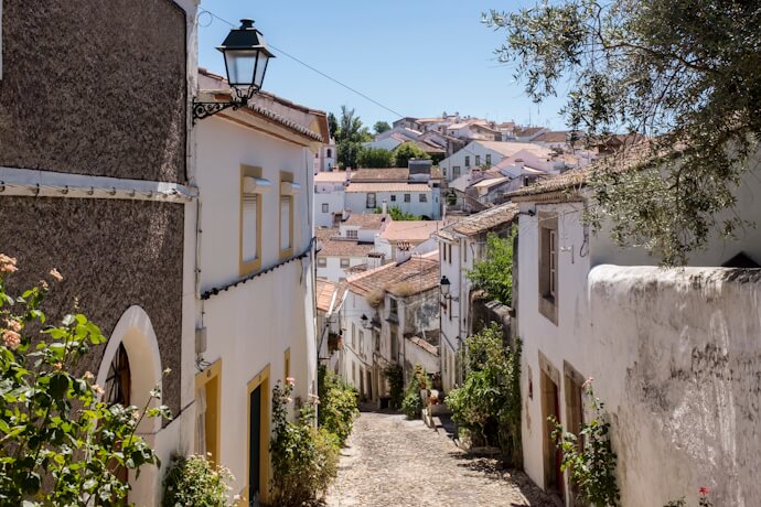 Whitewashed houses lining a cobbled street in the historic center of Castelo de Vide, Portugal.