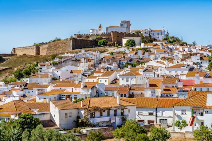 Whitewashed houses beneath the medieval castle walls of Estremoz, Portugal.