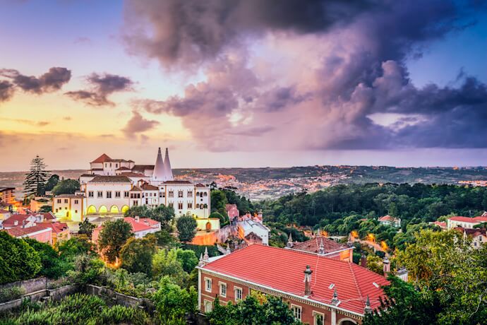 Dusk over Sintra, with Palácio Nacional de Sintra rising above red rooftops and green hills.