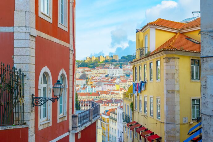 Colorful hillside streets of Lisbon with São Jorge Castle in the background.