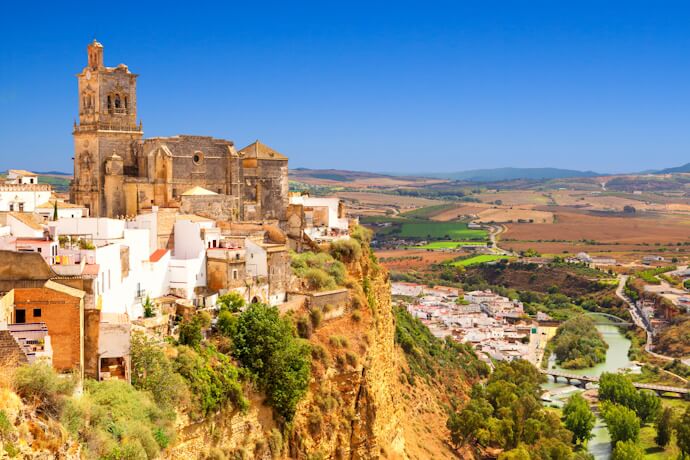 Arcos de la Frontera’s white houses and historic church dramatically set on a cliff overlooking the Guadalete River valley.
