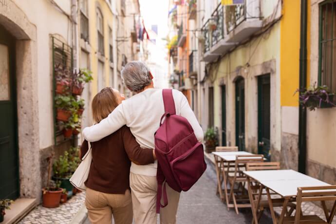 Older couple walking arm in arm down a narrow Lisbon street.