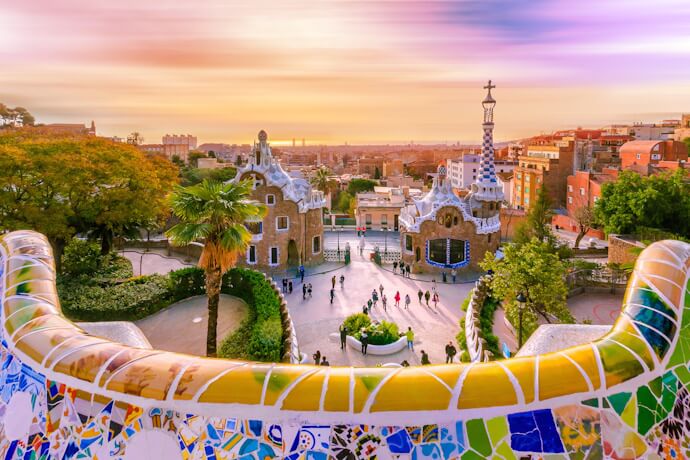 The monumental entrance and mosaic terrace of Gaudí's Park Güell overlooking Barcelona.
