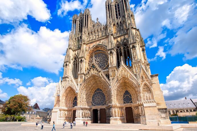 View of people passing by the grand Reims Cathedral in Reims, France