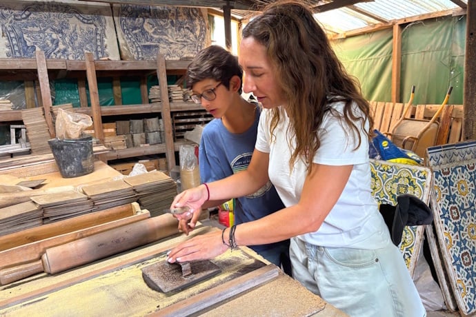 Visitors learning traditional azulejo painting techniques in a Portuguese ceramic workshop.