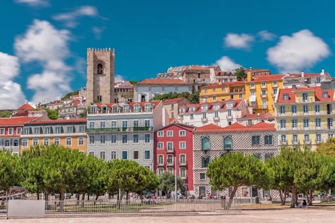 Colorful waterfront buildings and a historic church overlooking the Tagus River in Lisbon.