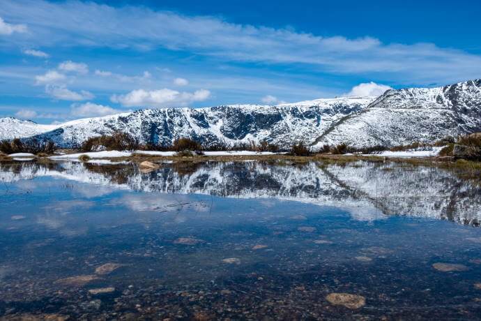 Snow covered mountains reflected in a lake in Serra da Estrela