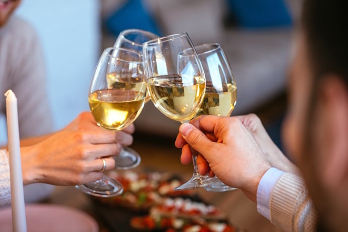 Glasses of crisp white wine clink together in a cozy tasting moment.