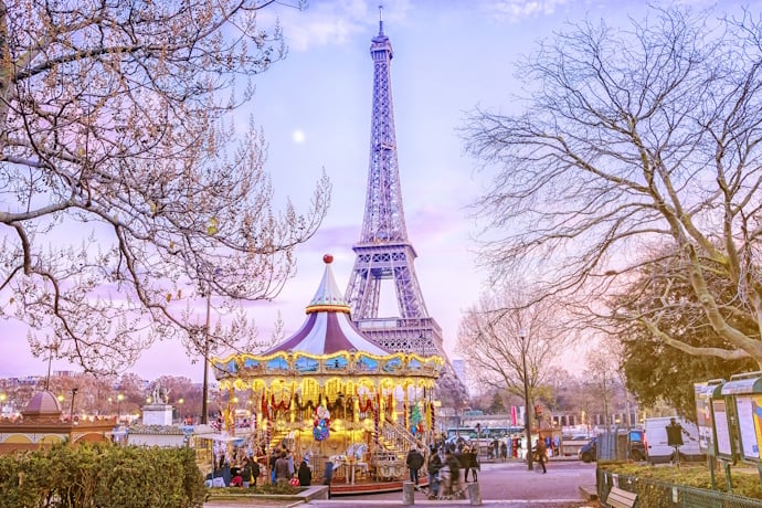 The Eiffel Tower rising behind a twinkling carousel in Paris.
