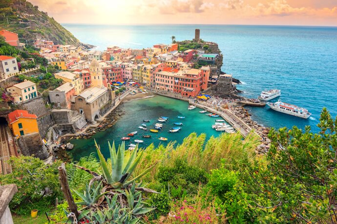 In Vernazza, with its harbor framed by pastel houses and boats floating in emerald waters.
