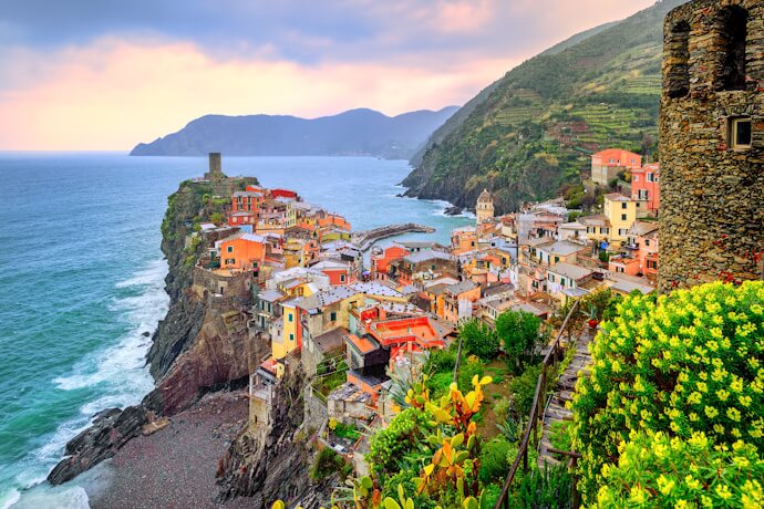A natural harbor in Vernazza, framed by a medieval tower and pastel houses.
