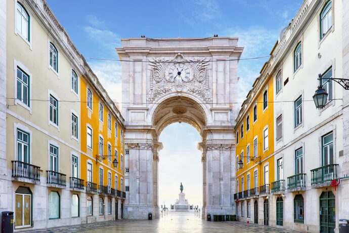 Rua Augusta Arch in Lisbon’s Baixa district with yellow Pombaline buildings.
