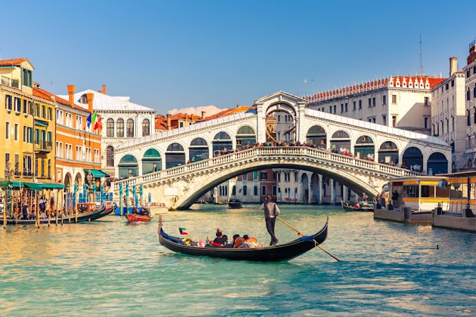 People in a gondola passing Rialto Bridge on Venice canal, Italy