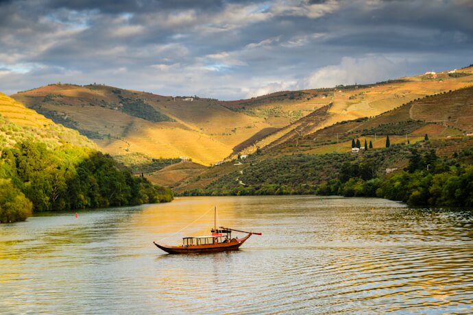 Traditional rabelo boat sailing along the Douro River at sunset