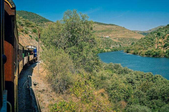 Historic train following the Douro River through terraced vineyard landscapes