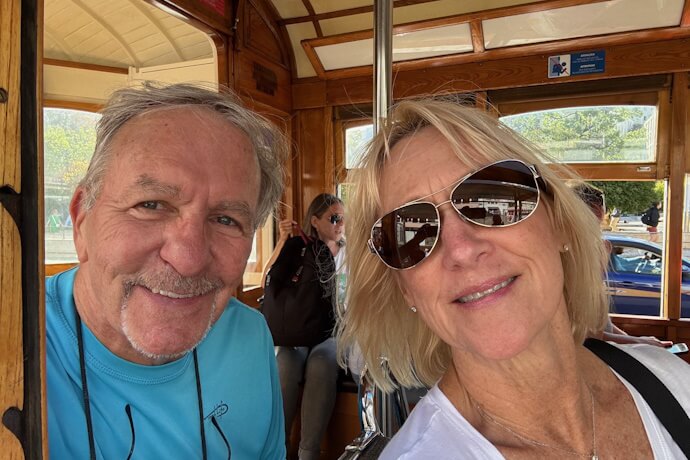 A smiling couple taking a selfie aboard one of Lisbon’s iconic wooden trams during a city ride.
